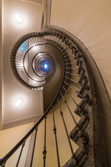 Looking Up Through Ornate Spiral Staircase Toward Blue Oculus with Iron Balusters