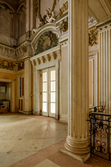 Ornate abandoned Belgian hall with fluted columns, cherub sculptures and marble floor - faded grandeur of a decaying palace interior