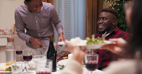 Friends are gathered at the table and eating to celebrate the beginning of winter vacation. A boy...