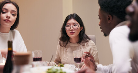 A multi-ethnic boy with a beard and a girl of Asian descent wearing glasses sit at a table. The brunette explains the method of preparation for the dish on the table, as she tells the guy about the