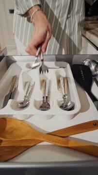 Vertical close up of unrecognizable housewife putting cutlery into plastic silverware organizer