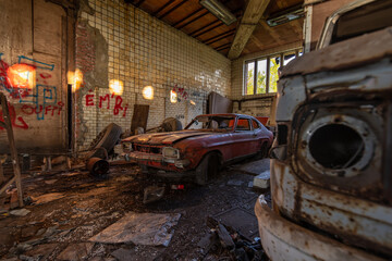 Rusty vintage coupe inside a derelict tiled garage with graffiti and sunlit decay - abandoned interior at Charbonnage du Renard, Belgium