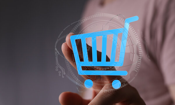 Hand holding a shopping cart icon with a technological digital interface. Represents online retail, e-commerce, and digital buying. Perfect for