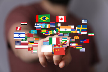 Person's hand touching and interacting with a collection of various national flags symbolizing global connections, world peace, international co