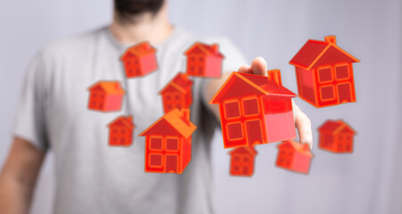 Conceptual image of a man's hand touching digital home models, representing real estate, investment, and property ownership.