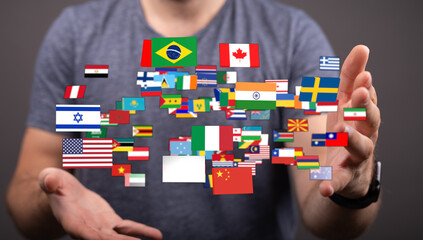 A man's hand holding up floating flags of different countries, symbolizing globalism, travel, and...