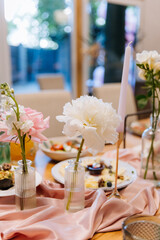 Close up of elegant wedding table with white peony, pink rose and candle on silk runner