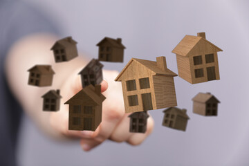 Close-up shot of a hand holding and interacting with multiple wooden houses. Great for real estate,...