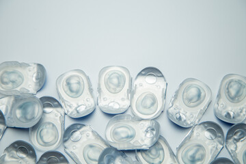 Many daily contact lenses in a disposable protective case lie at the bottom on a white background with space for text. The concept of ophthalmology, vision correction, eye care. High quality photo