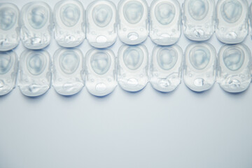 Several rows of daily contact lenses in a disposable protective case lie on top of a white background with space for text. The concept of ophthalmology, vision correction, eye care. High quality photo