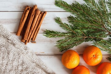 Cinnamon sticks, fresh oranges and pine branches create a bright rustic holiday arrangement on white wood