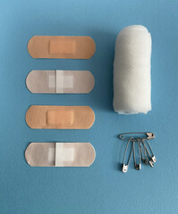Plasters, Gauze Bandage and Safety Pins on Blue Background for First Aid