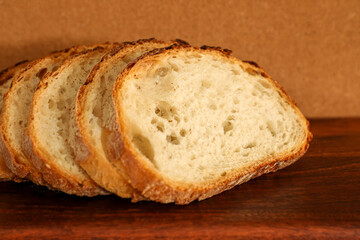 Sourdough slices arranged in a gentle arc on a wooden board evoke a homestyle, wholesome atmosphere.