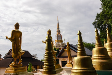 Golden Buddha statues and gleaming stupas are arranged on a terrace, offering a spiritual and...