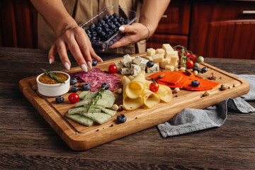 serving different snacks from salami and cheese on a wooden board for alcohol