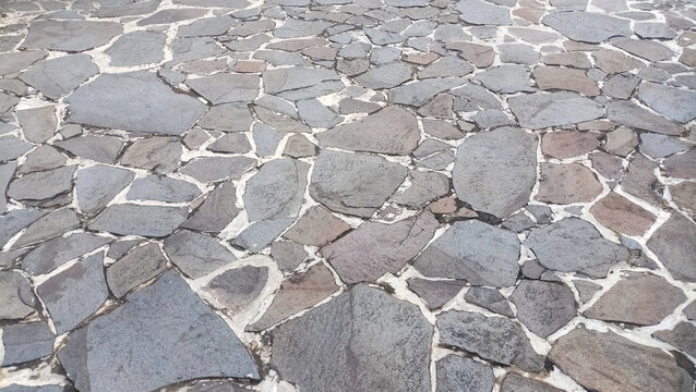 Texture of dark gray natural stone paving floor with irregular shapes.
