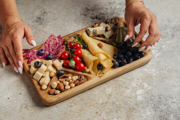serving different snacks from salami and cheese on a wooden board for alcohol