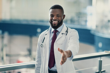 Portrait of handsome smiling young african american doctor in workwear and stethoscope...