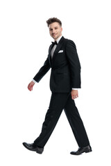 attractive young man in black tuxedo smiling and walking