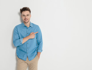 Smiling young casual man pointing finger to the side