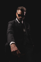 Obraz premium Elegant man in suit sitting with one hand in pocket