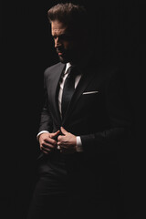 Elegant man closing his suit and looking away