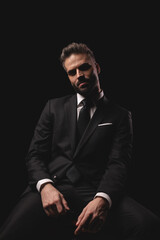 Serious man in suit sitting and holding glasses