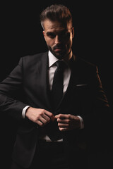 Serious man closing his suit jacket