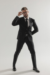 Serious man standing and fixing his glasses