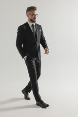 Side view of serious man walking with hand in pocket