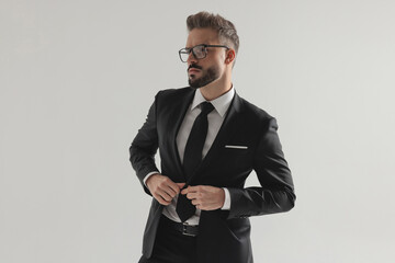 Stylish man buttoning his suit and looking to side