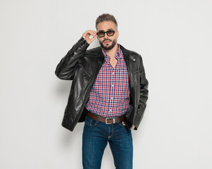Stylish man fixing sunglasses with hand in pocket