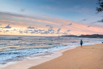 Tourist walking alone on sandy beach at sunset, enjoying beautiful ocean view in kauai, hawaii