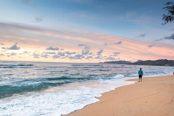 Tourist walking alone on sandy beach at sunset, enjoying beautiful ocean view in kauai, hawaii