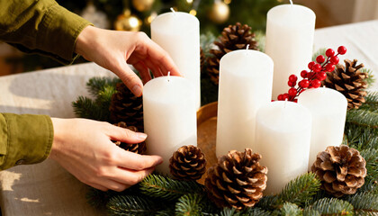 Hands arranging a festive Christmas centerpiece with white candles. Creating a traditional advent wreath with fir branches and pinecones. Holiday season DIY decoration concept