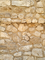 Old stone wall texture with rough beige and white stones. Distressed architectural backdrop.