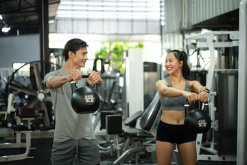 Fototapeta premium Fit and muscular man and woman focused on lifting a kettlebell during an exercise class