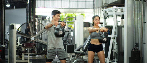 Fit and muscular man and woman focused on lifting a kettlebell during an exercise class