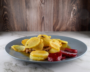 Sailor steak. Yellow potatoes are arranged on a blue plate alongside sliced beets. The dish highlights a home-cooked meal, appealing with its vibrant colors and fresh ingredients