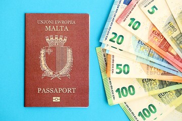 Malta passport lies with euro money banknotes on blue background close up. Salary and pension in...