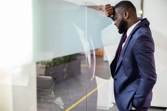 Exhausted bearded young black businessman leaning on window glass at office, looking at the street, having difficulties with business, need for creative solutions, panorama with copy space - Powered by Adobe