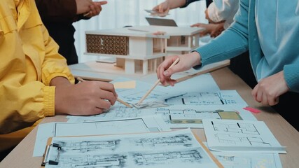 A dynamic scene of architects and designers collaborating in a creative workspace, drafting plans and building models while surrounded by blueprints and materials. SACTR - Powered by Adobe