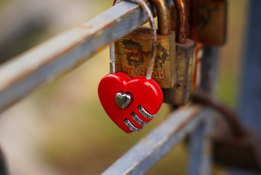 Red heart-shaped love lock hanging on a metal railing, a romantic symbol of affection and
commitment placed on a city bridge.