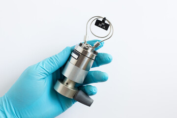 A scientist's hand in a blue glove holds a manual HPLC injection valve assembled with a 20 microliter sample loop. Equipment for high performance liquid chromatography analysis in a science lab. 