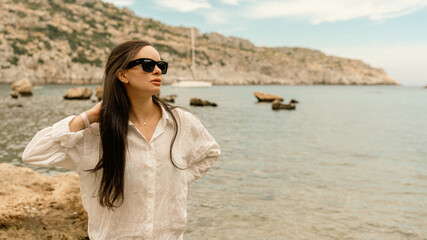 Woman walking happily on a beautiful beach wearing a stylish cover-up over her bikini. Sunny day, ocean waves, and relaxing vacation atmosphere.