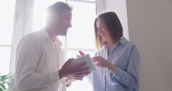 Valentine day gift, loving couple enjoying intimate close emotion, man, woman celebrating, hugging with love, tenderness, holding paper handmade greeting card, red heart, smiling, pair trust, harmony - Powered by Adobe