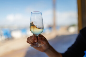 Hand holding glass of manzanilla sherry swirling liquid