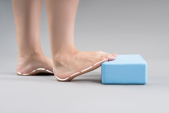 Individual balance training on a blue block with bare feet, demonstrating foot position and stability on a gray background