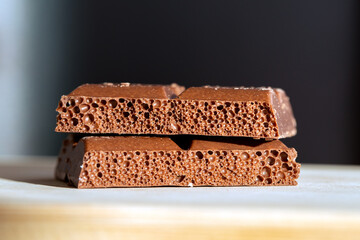 A stack of milk chocolate in a close-up shot. Sweet milk chocolate with a visible texture and air bubbles, captured in detailed close-up