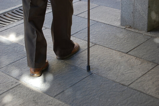 Person Walking with a Walking Stick in an Urban Environment